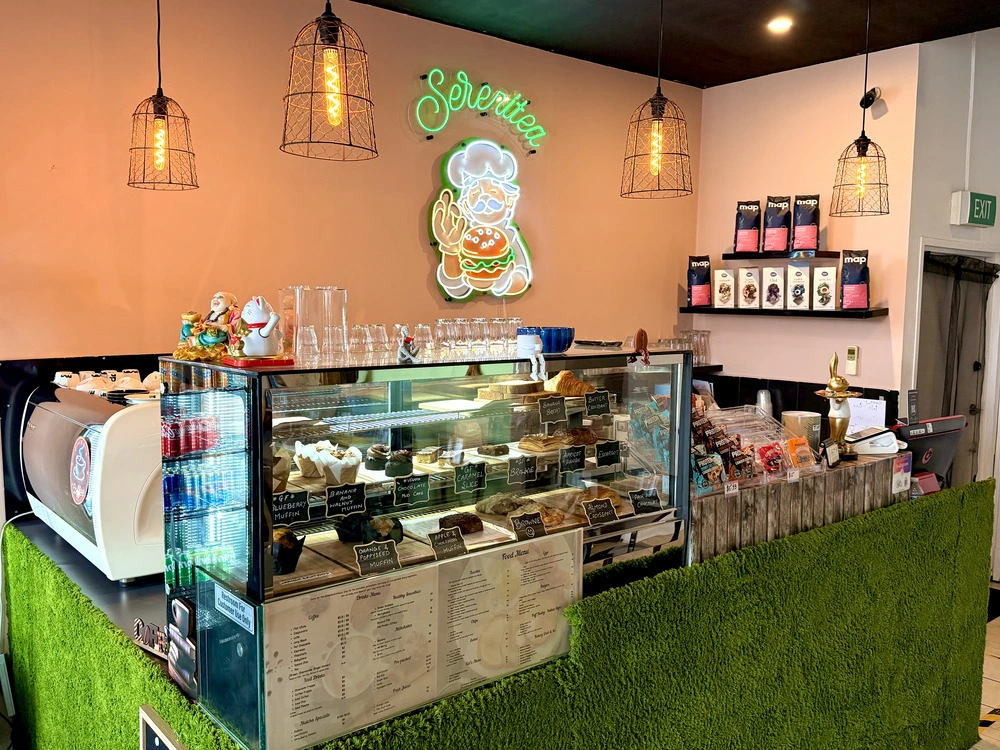 Serenitea counter, pastry case and neon sign